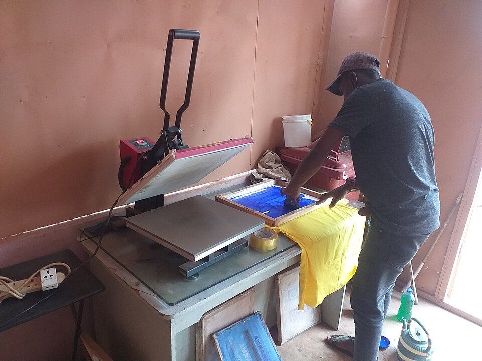 Plancha de transferencia térmica junto a una camiseta en un taller de estampación (imagen de archivo)